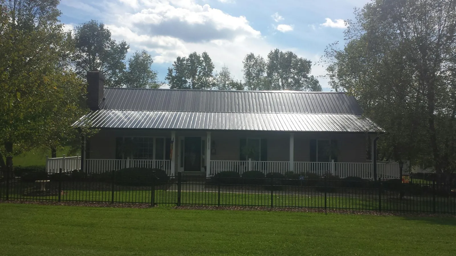 Gray metal roof on a brick ranch with a full width front porch — Gutter Guard Installation work by our crew in Lodi